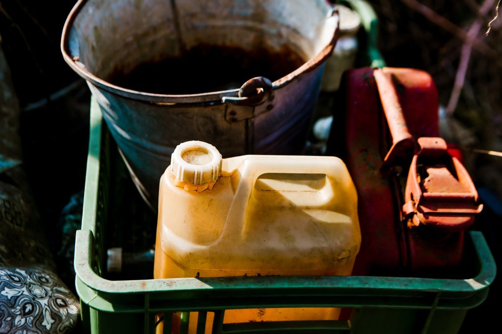 Improvised field servicing setup using fuel containers, buckets, and manual fluid handling equipment with increased risk of spills and contamination