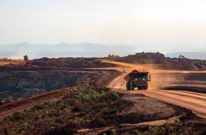 Open-cut mine site with a haul truck operating on a dusty road in harsh mining conditions