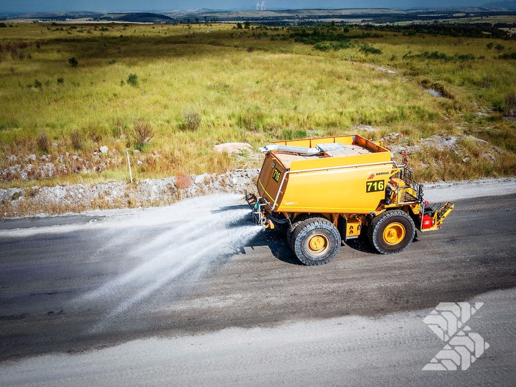 Water cart spraying water across a mining haul road for effective dust control and environmental compliance.