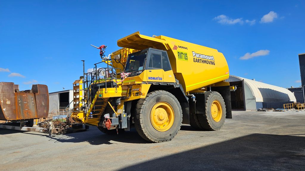 Parked in a depot yard, a Paramount-branded Shermac off-road water cart awaits deployment.