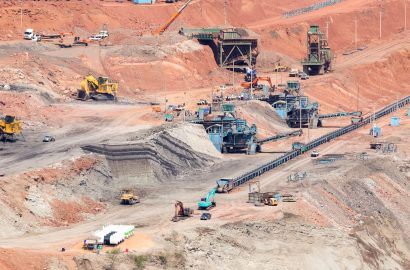 Mining and civil worksite with heavy machinery, conveyors and excavation equipment operating across a large open-cut mine environment