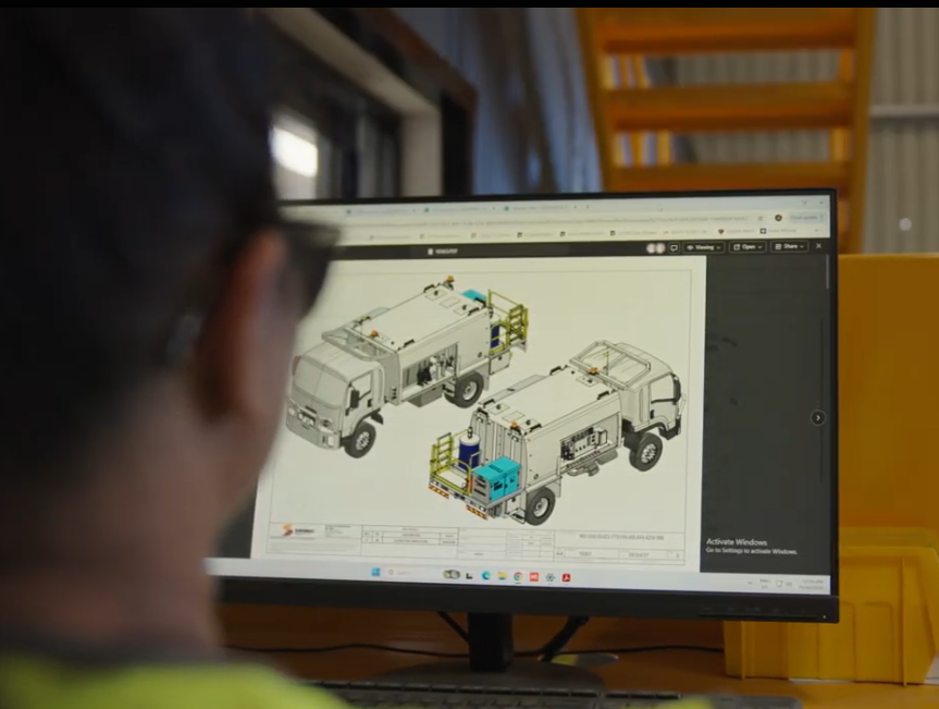 Engineer reviewing CAD drawings of a water truck build on a computer monitor
