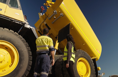 Two workers in hi-vis inspecting a water tank body fitted to a Komatsu haul truck