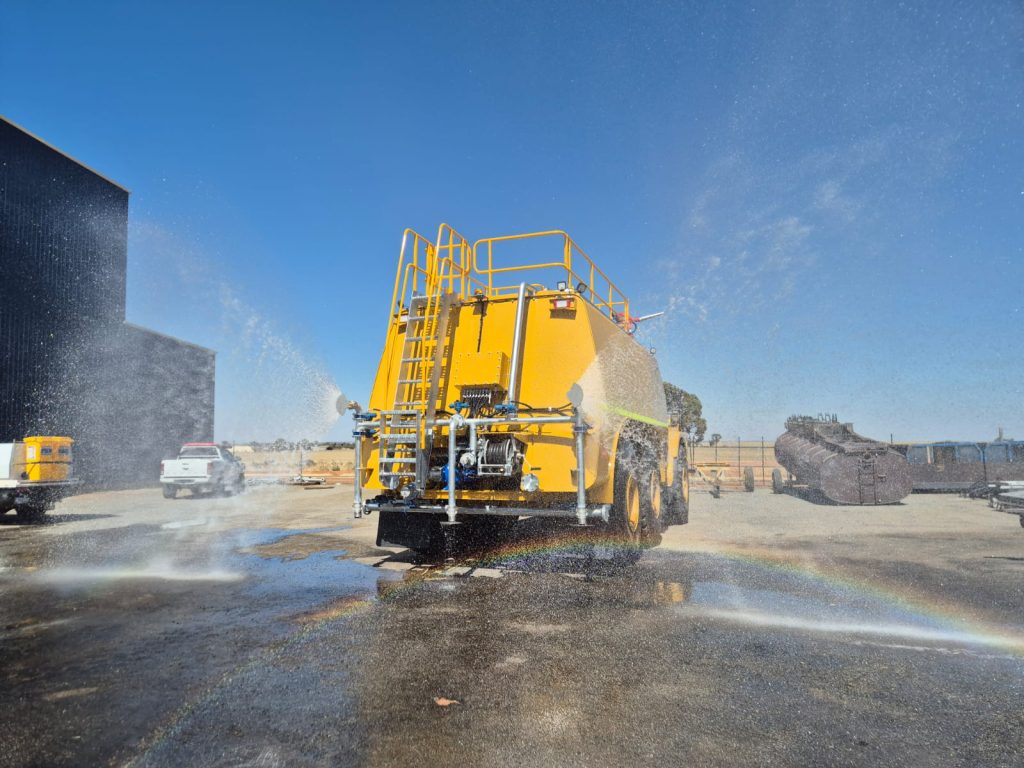Shermac articulated water cart with chassis-matched tank capacity and rear spray system operating on a mine site.